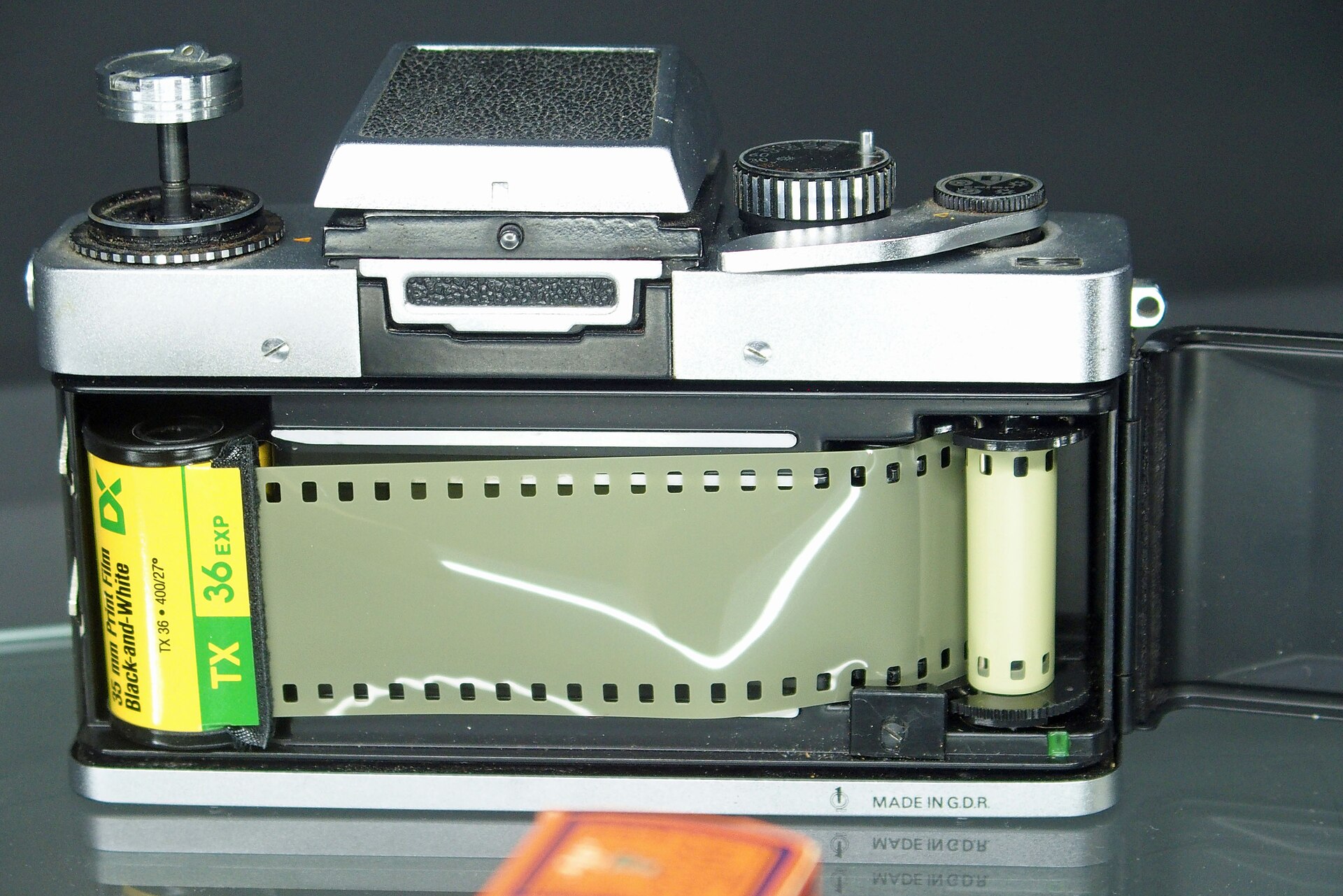 一卷 135 胶片被装进 35mm 单反相机的后仓，机背打开